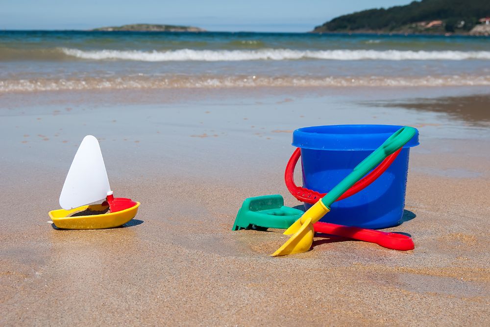 Juguetes de playa en arena frente al mar.