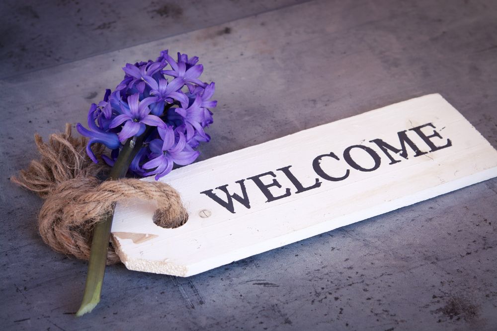 Cartel kit de bienvenida con flores moradas.