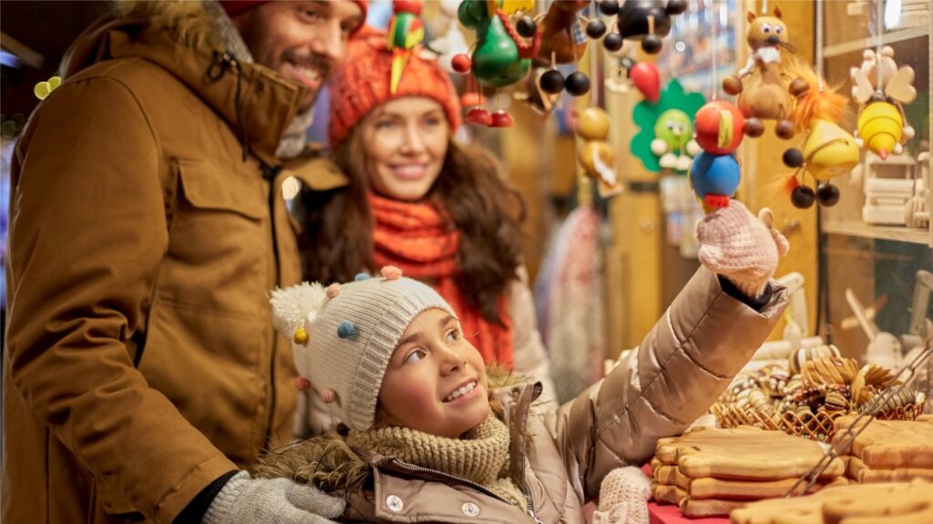 Familia en mercado navideño con juguetes coloridos.