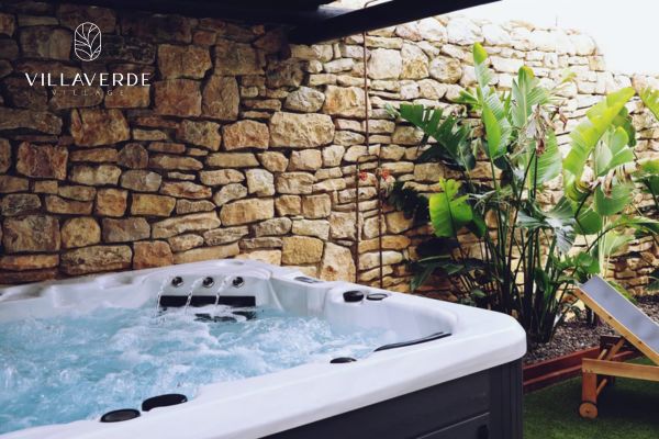 Jacuzzi exterior junto a muro de piedra y plantas tropicales