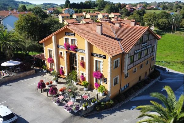 Posada rural amarilla con terraza floral y tejado rojo